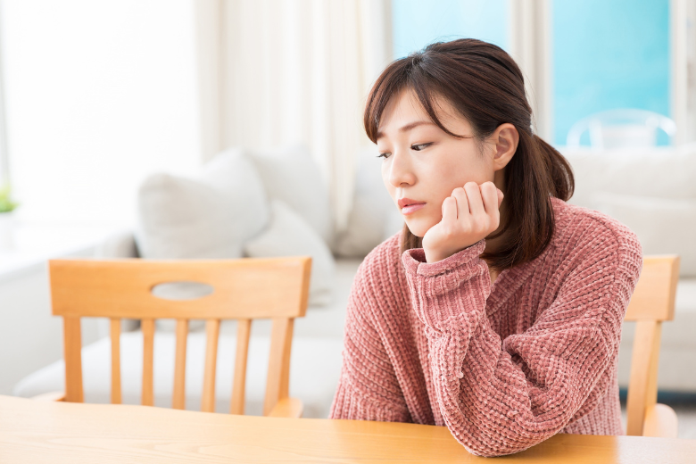 ダイニングテーブルで「いい人なんだけどなんか違う」とモヤモヤした表情で悩む婚活中の女性